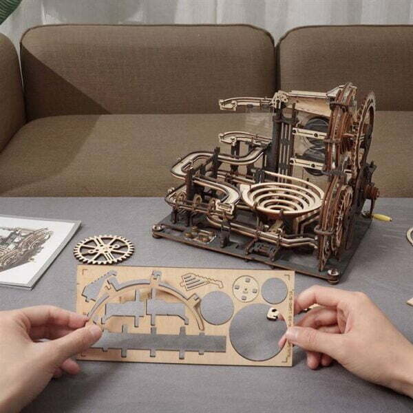 Une personne assemble un modèle en bois 3d d'une machine de puzzfever.