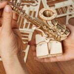 Une personne crée un modèle de puzzle 3D en bois représentant un saxophone.