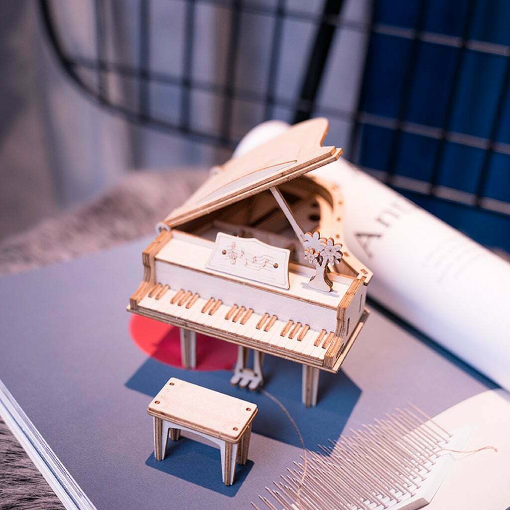 Un puzzle 3d en bois représentant un piano posé sur un livre.