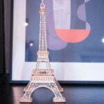 La maquette en bois de la Tour Eiffel est posée sur une table à côté d'un tableau.