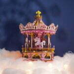Une maquette rose du Carrousel musical enchanté posé au sommet des nuages.