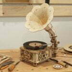 Un puzzle robotique 3D représentant un gramophone classique avec 3 vinyles en bois est posé sur une table.