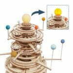 Une maquette de puzzle Rokr 3D d'une tour d'horloge en bois présentant le système solaire mécanique.