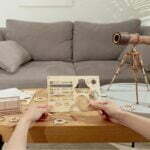 Une personne assemble un puzzle 3D représentant un télescope Rokr sur une table basse.