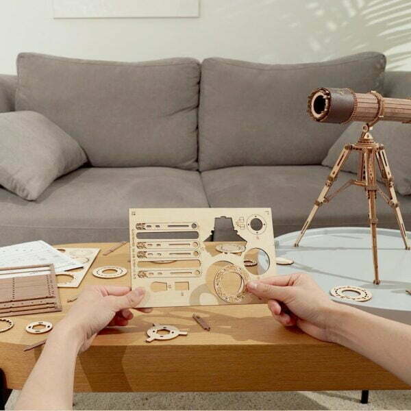 Une personne assemble un puzzle 3d reprÃ©sentant un tÃ©lescope rokr sur une table basse.