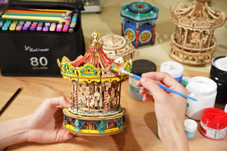 Guide d'assemblage des puzzles 3D en bois lazy Une personne peint un carrousel en bois sur une table à l'aide de Robotime.