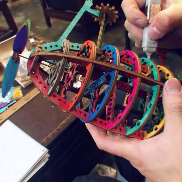 Guide d'assemblage des puzzles 3D en bois lazy Une personne assemble un modèle 3D de puzzle ROKR coloré d'un bateau.