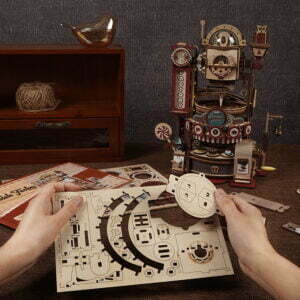 Une personne construit une maquette de puzzle 3d du circuit à billes : robot chocolaterie.