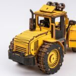Une maquette en bois d'un bulldozer jaune sur fond blanc.