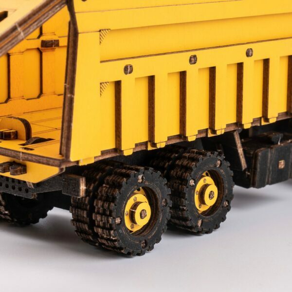 Un modèle en bois d'un camion à benne jaune sur fond blanc.