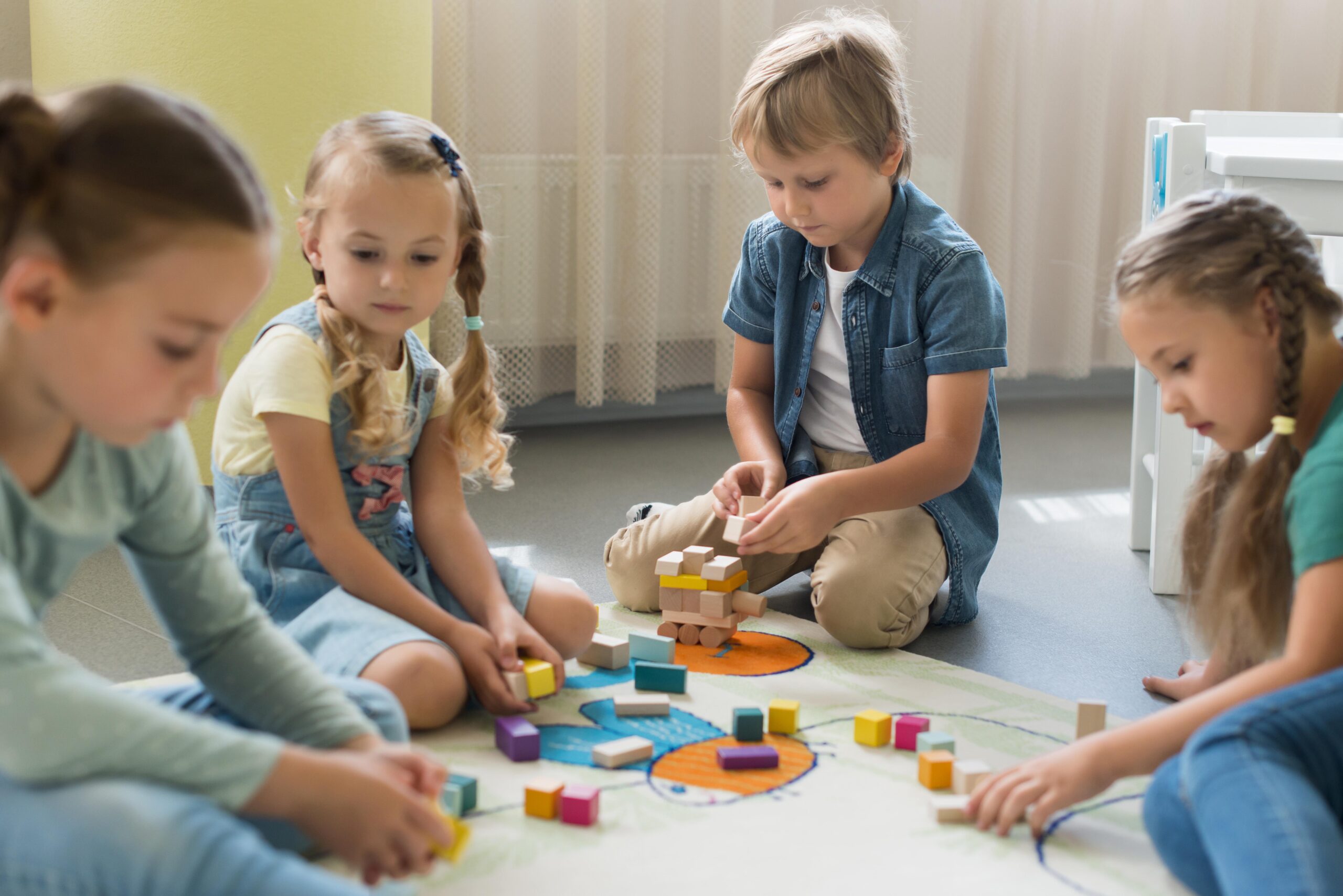 Un groupe d'enfants jouant avec des puzzles éducatifs au sol à différents âges.